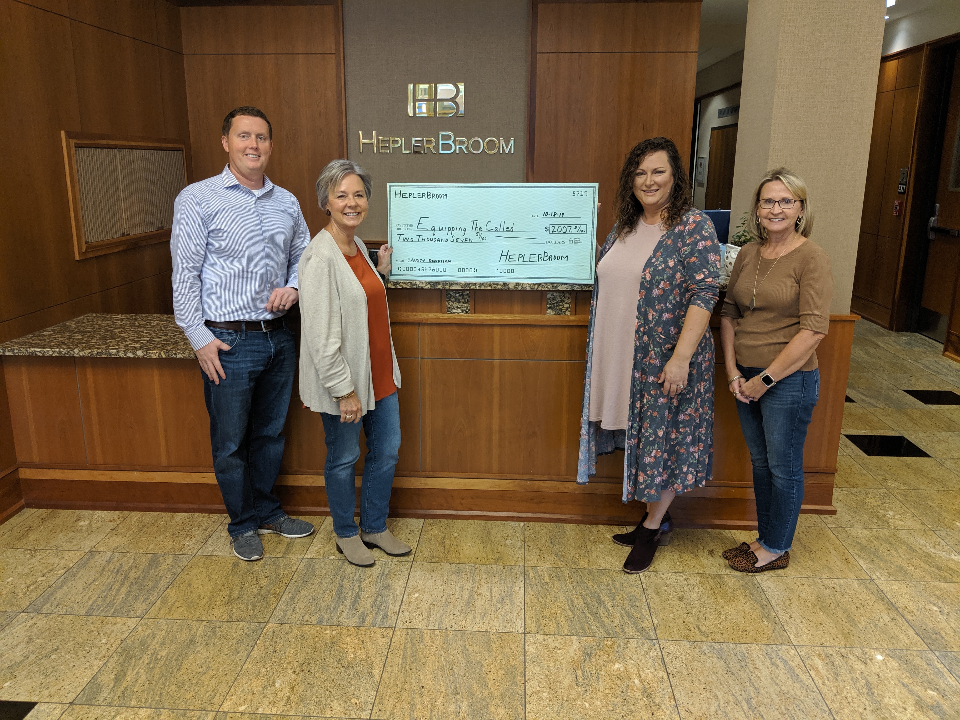 photograph of HeplerBroom attorney Matt Champlin, paralegal Sandy Hammett, and Marketing & Recruiting Coordinator Jody Robbs presenting check to Julie Tracy, co-founder of Equipping the Called