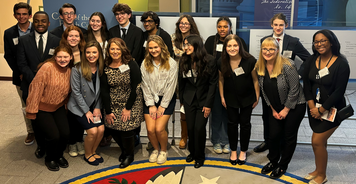 group of students standing behind an official seal embedded in a floor