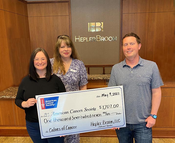 2 women and a man with 1 woman holding large check made out to American Cancer Society