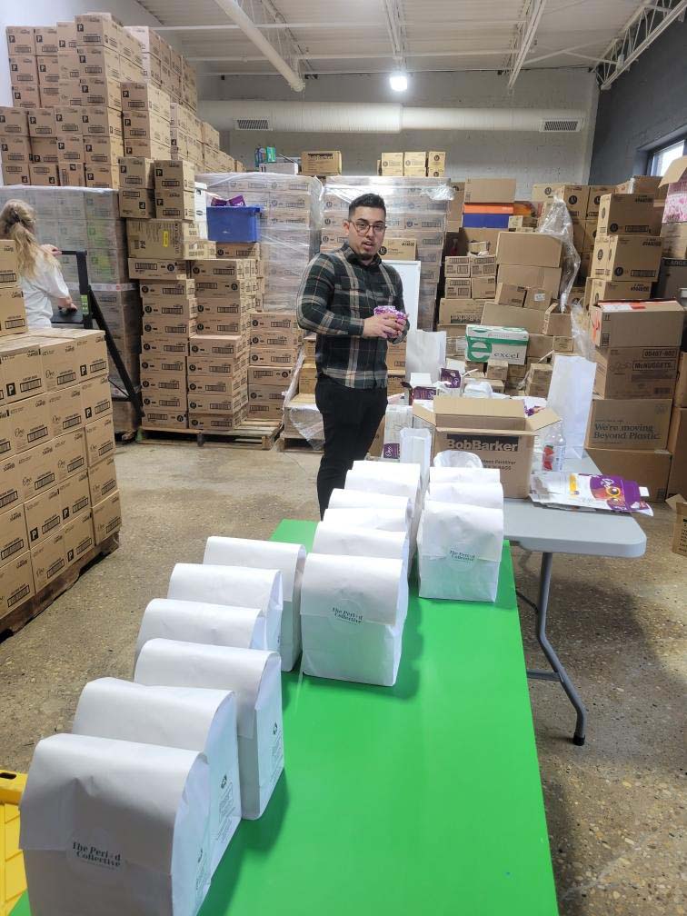 man in background standing behind table filled with white bags
