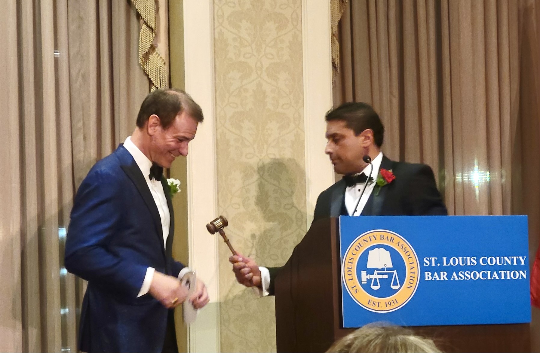 one man passing a gavel to another man