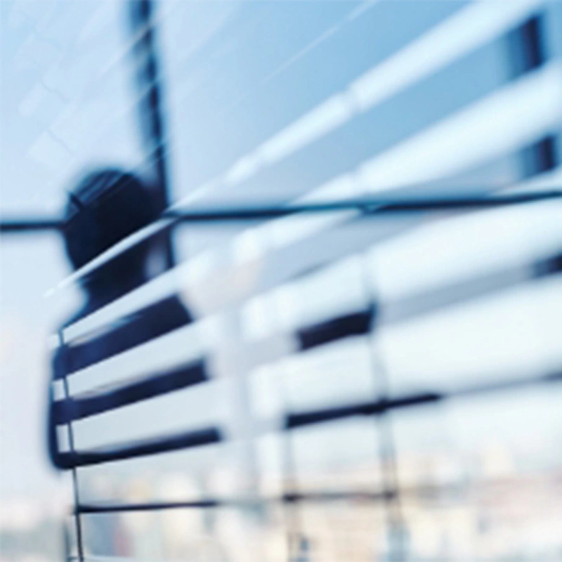 side view of partially opened blinds on a window with a person in corner